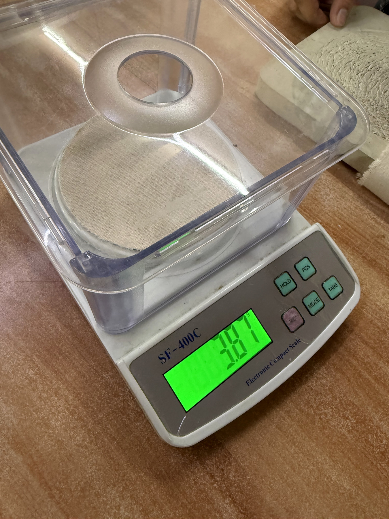 Cotton fabric specimen undergoing GSM verification on a precision weighing scale
